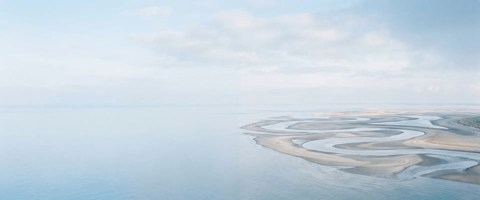 Narcistisch gedrag herkennen: zandbanken en geulen die bij laagwater zichtbaar worden in een wijde riviermonding