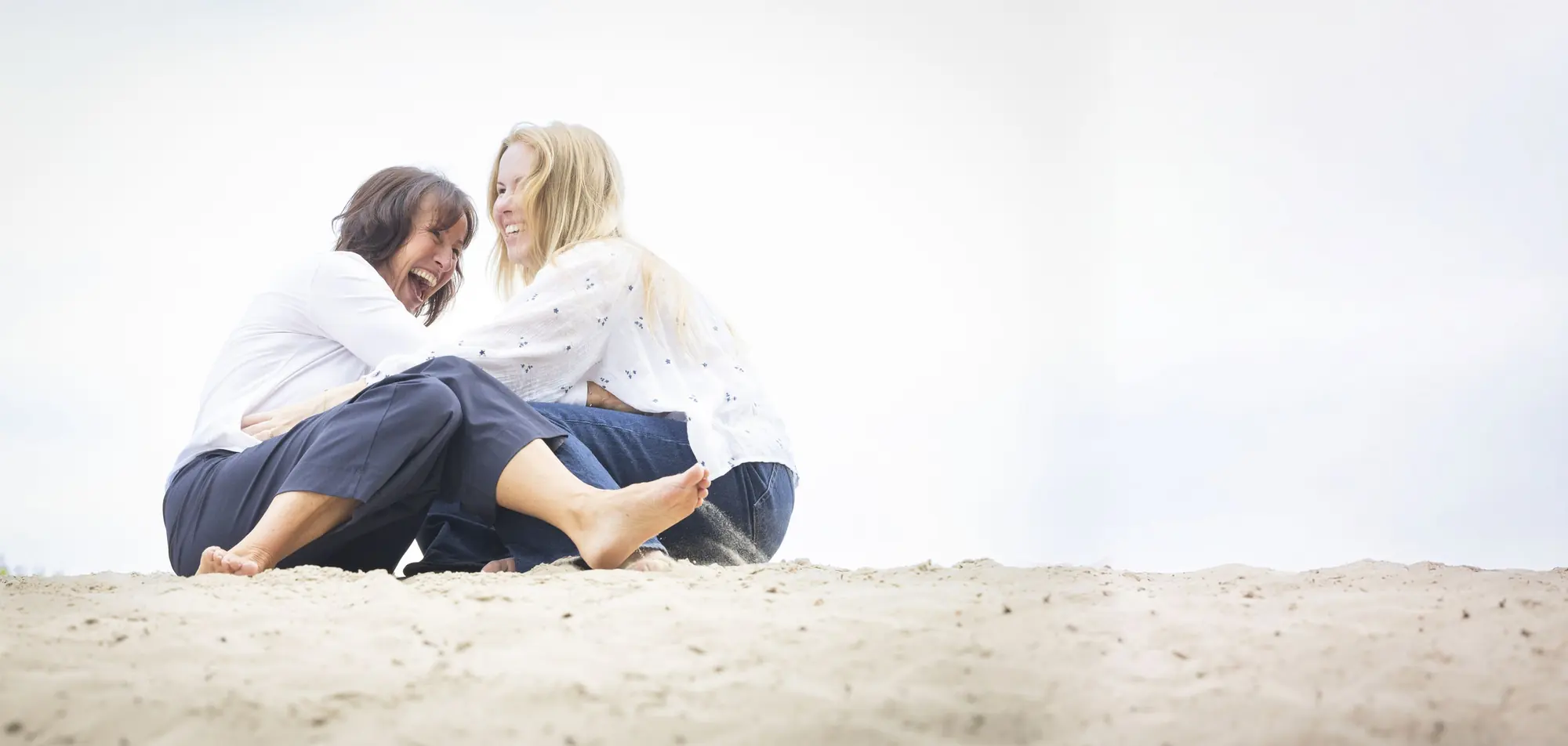 Jacqueline Lammerts in gesprek, lachend samen op het zand