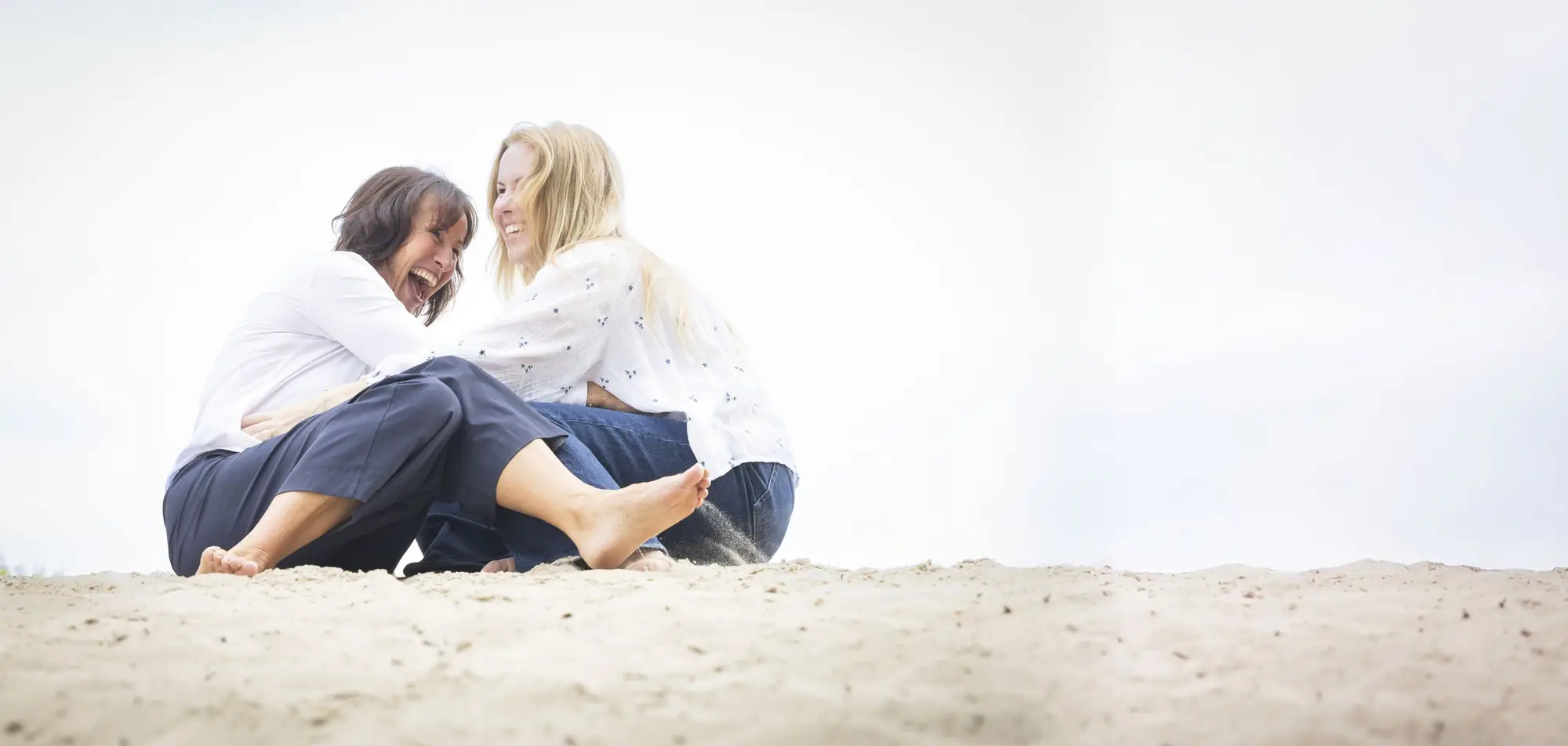 Jacqueline Lammerts lacht samen met een vrouw in het zand