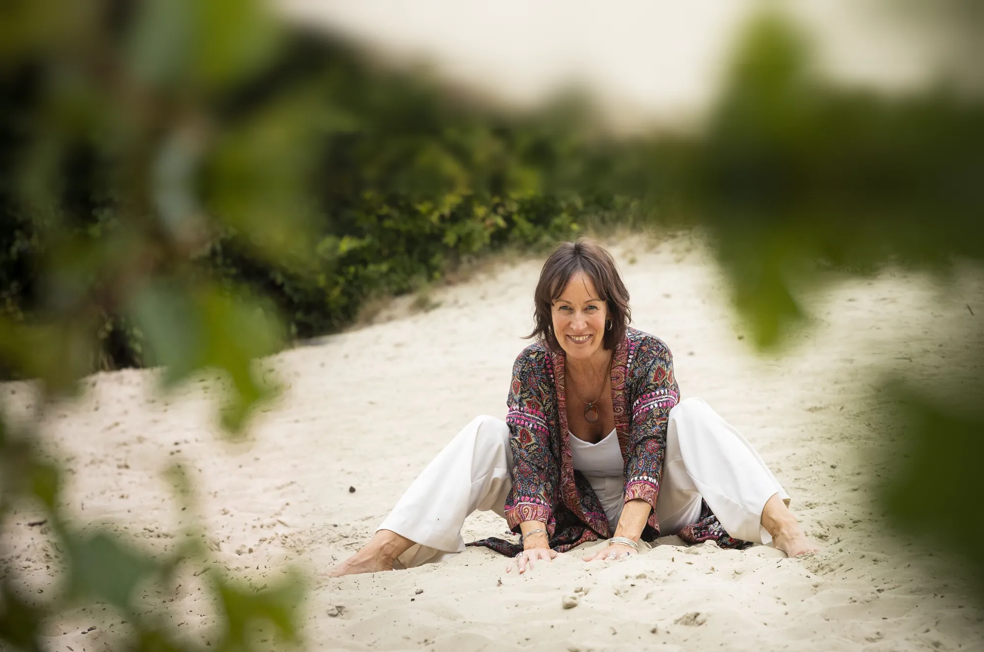 Jacqueline Lammerts zit lachend in het zand
